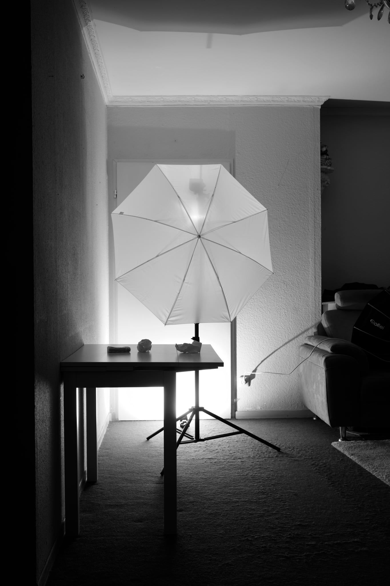 Studioaufbau im Wohnzimmer: Tisch vor heller Wand, dahinter ein Blitz mit Durchlichtschirm