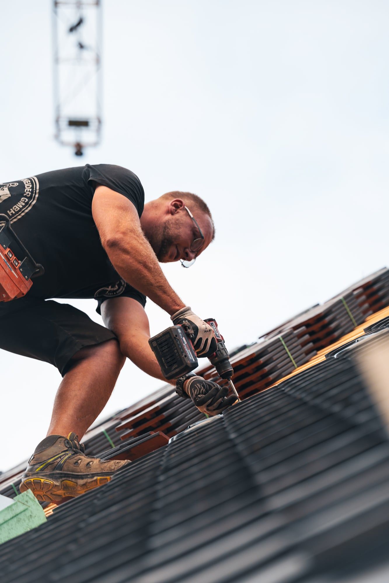 Dachdecker arbeitet auf einem steilen Dach vor hellem Himmel – Businessfotos in München