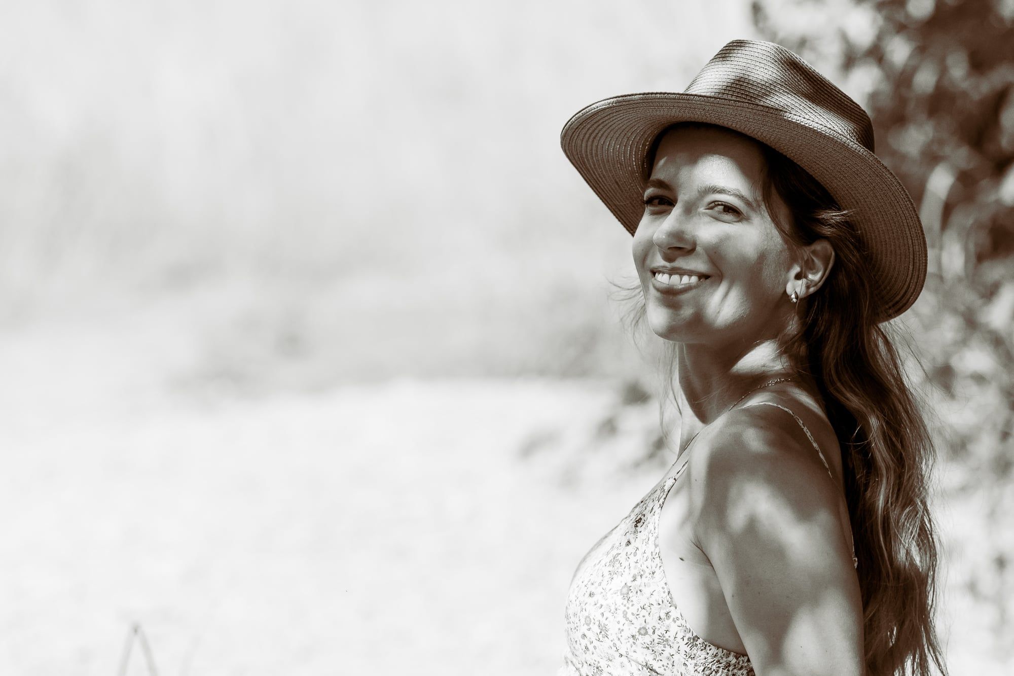 Lachende Frau mit Hut im hellen Sommerlicht, in Sepia – Portrait in Augsburg