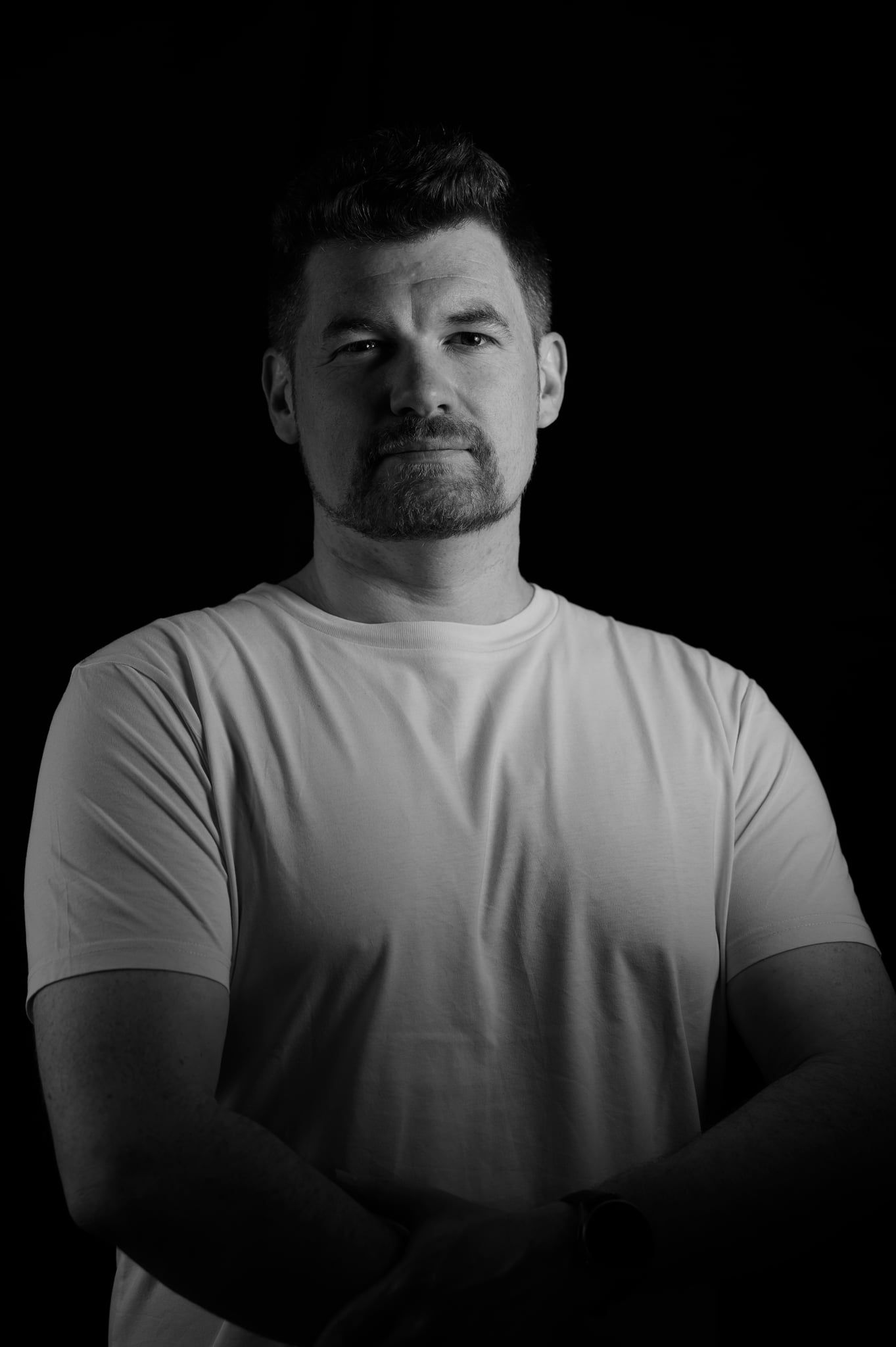 Low-Key-Portrait von Daniel mit verschränkten Armen, durch das zweite Licht gleichmäßiger ausgeleuchtet