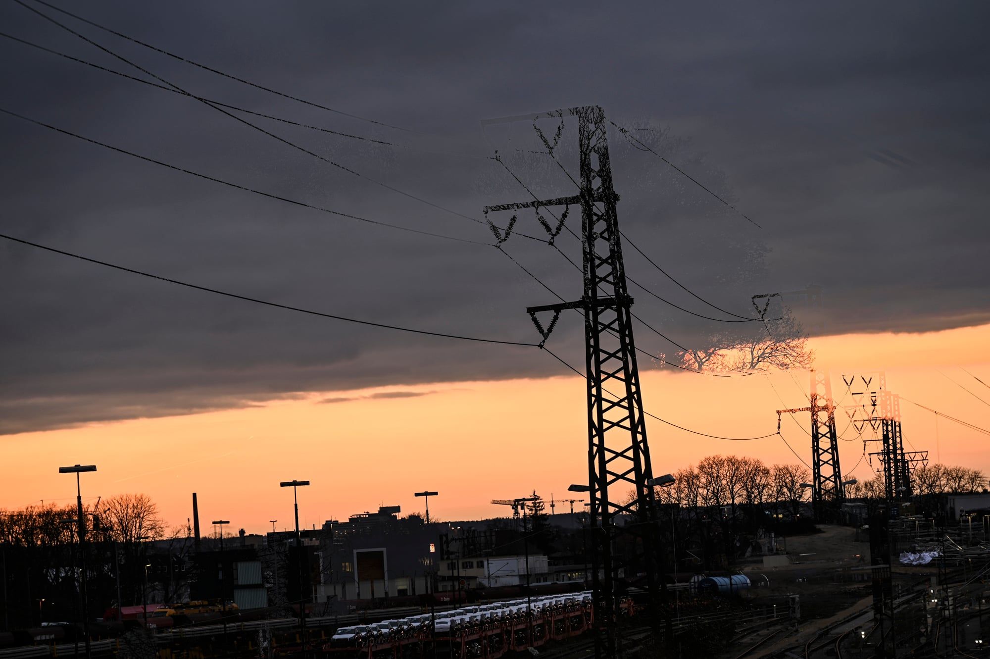 Strommast über den Gleisen am Augsburger Hauptbahnhof vor orangem Sonnenuntergang
