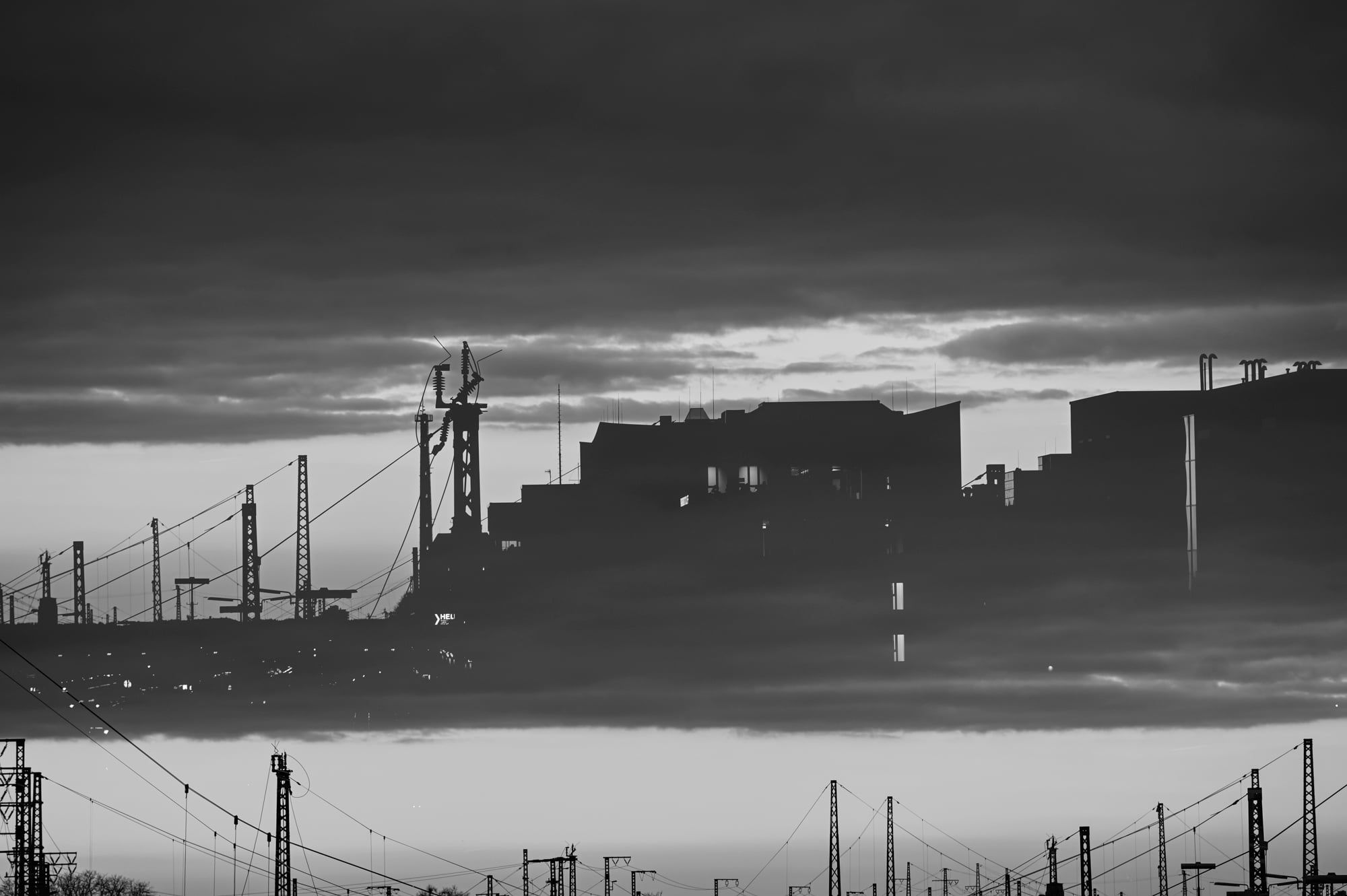 Schwarzweiße Mehrfachbelichtung: Stadtsilhouette gespiegelt zwischen Himmel und Gleisen – Augsburg