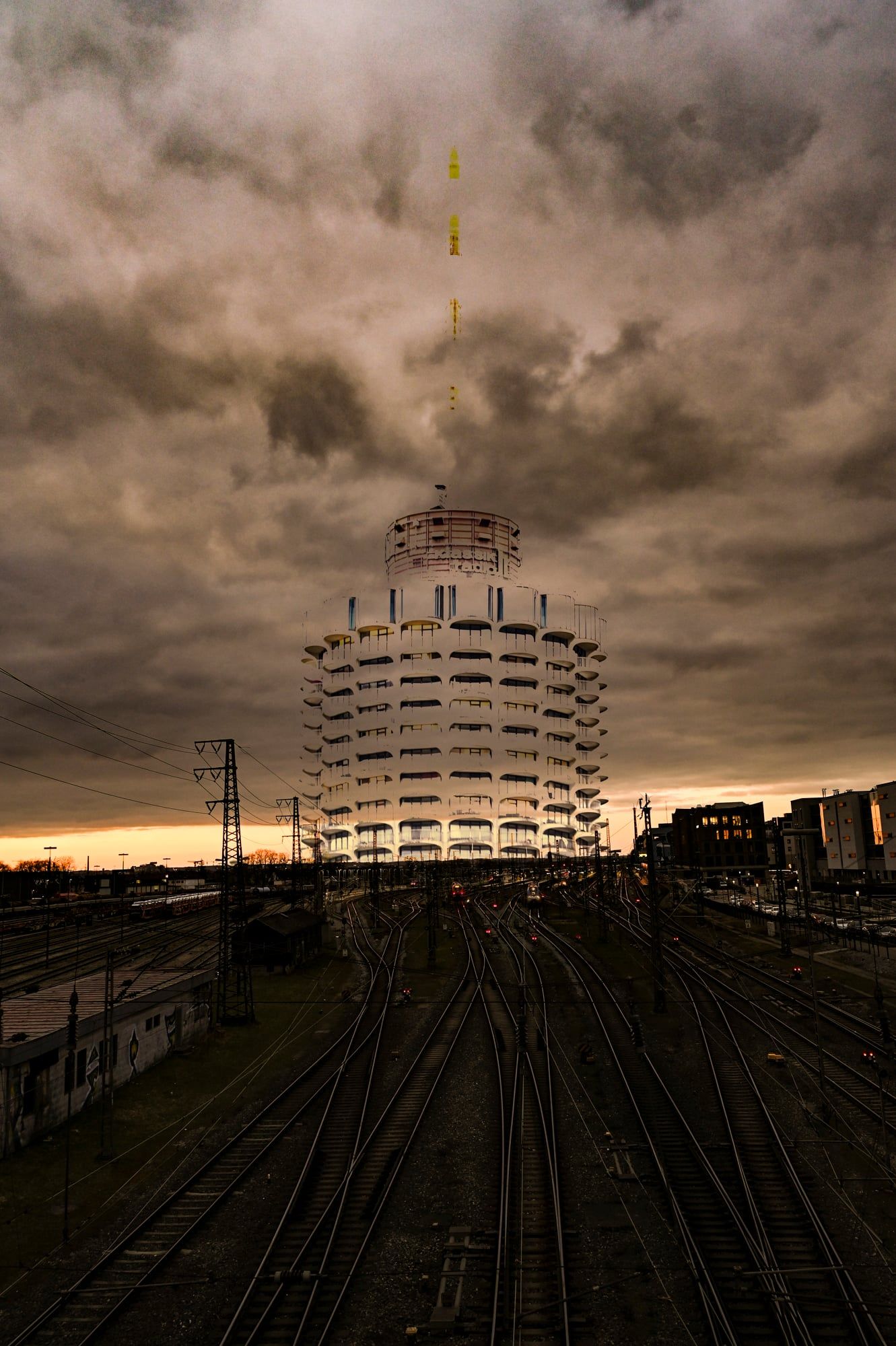 Rundes Hochhaus über den Gleisen am Augsburger Hauptbahnhof unter dramatischen Wolken