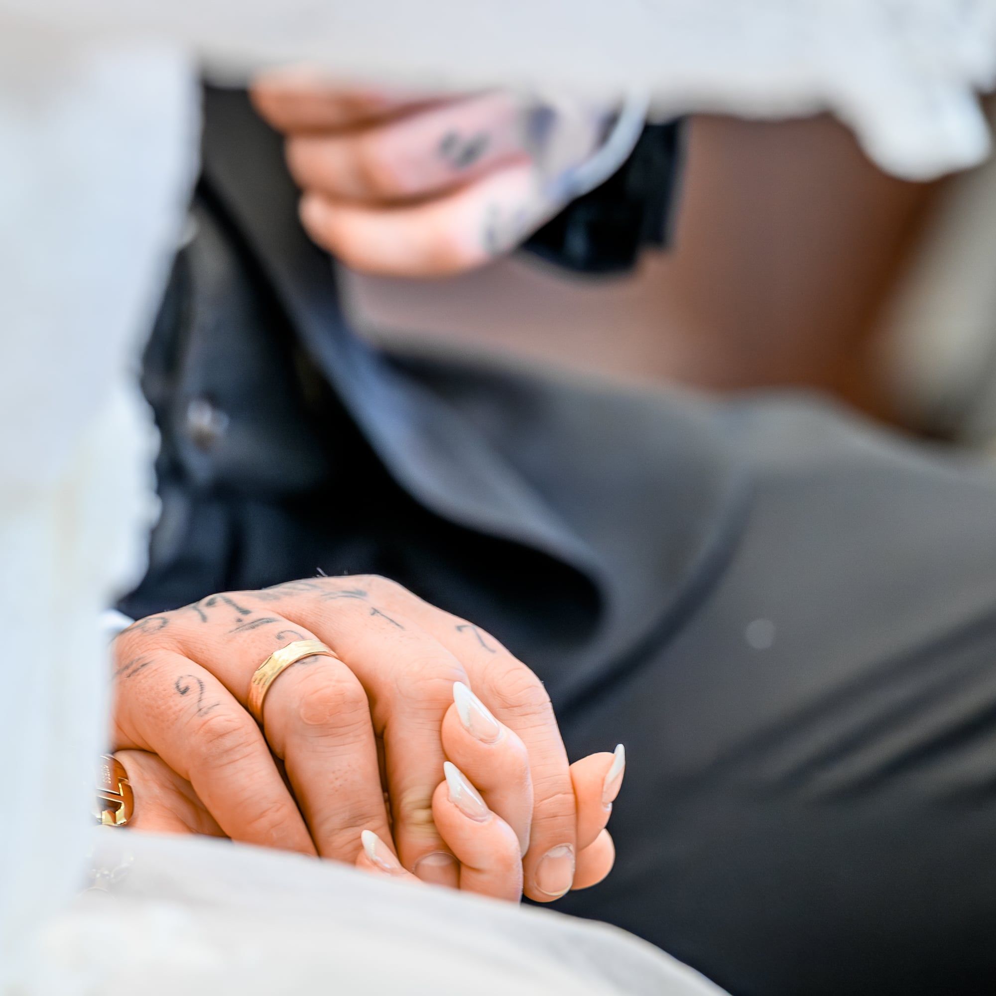 Nahaufnahme ineinandergelegter Hände mit Ehering auf dem Ärmel des Bräutigams – Hochzeit in Augsburg