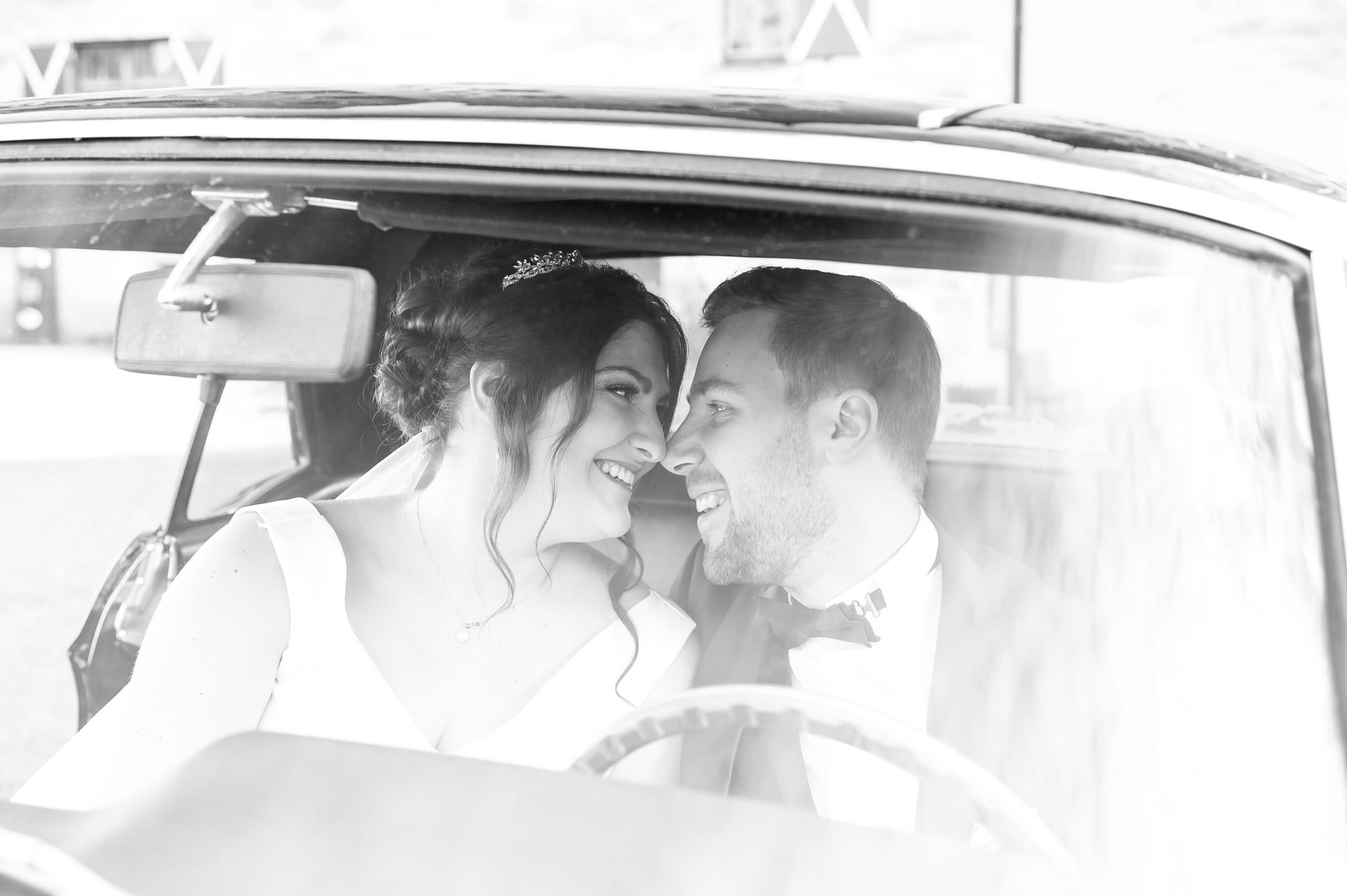 Brautpaar lehnt Wange an Wange in einem Oldtimer, Schwarzweiß – Hochzeit in Wittislingen