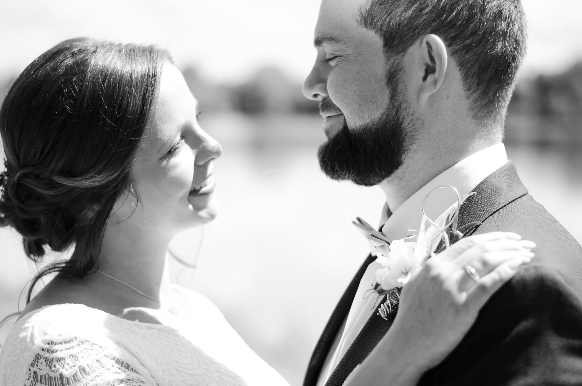 Brautpaar sieht sich lachend an, im Hintergrund ein See, Schwarzweiß – Hochzeit in Augsburg