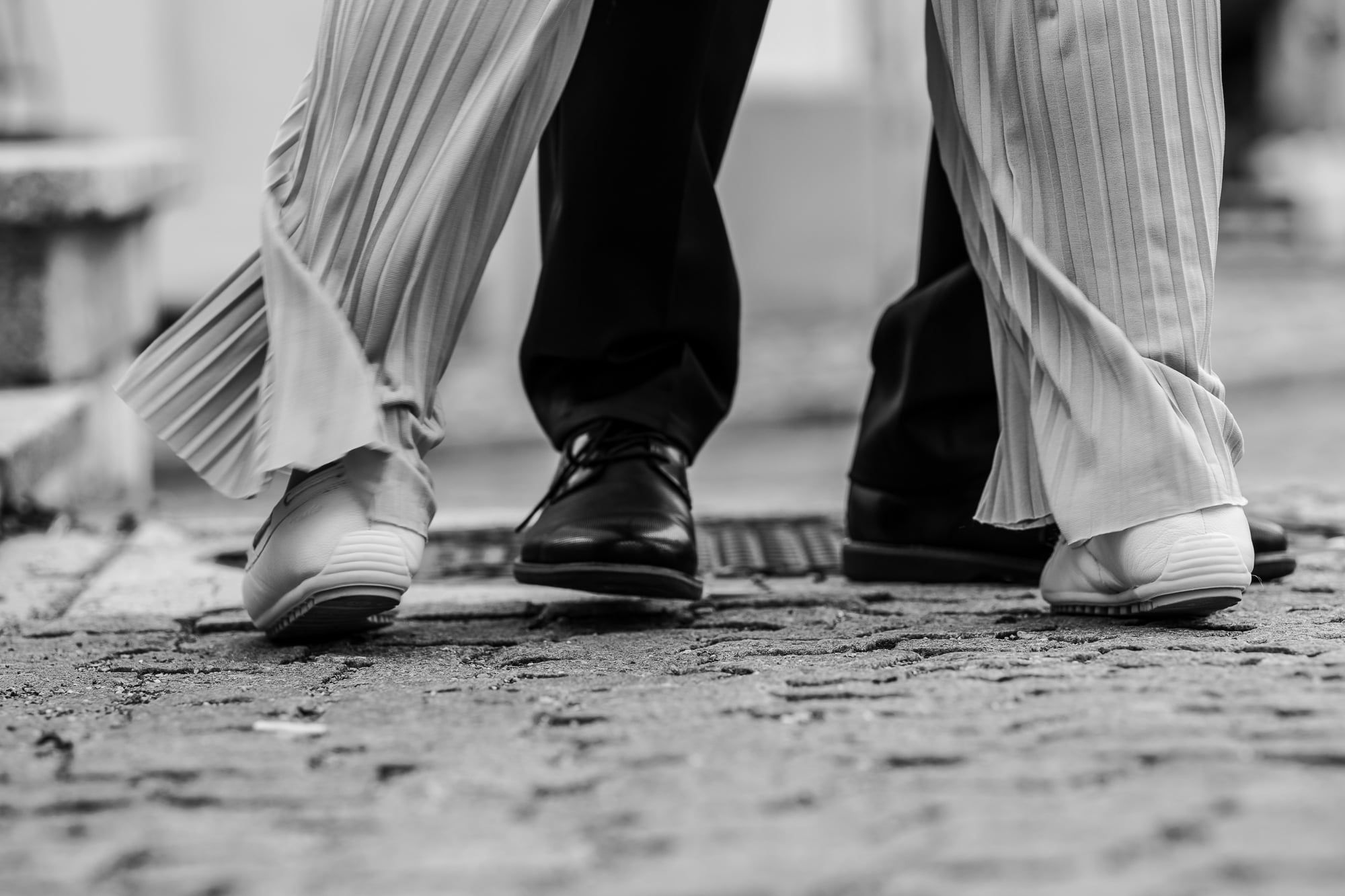 Füße des Brautpaars beim Tanz auf Kopfsteinpflaster, Schwarzweiß – Hochzeit in Friedberg