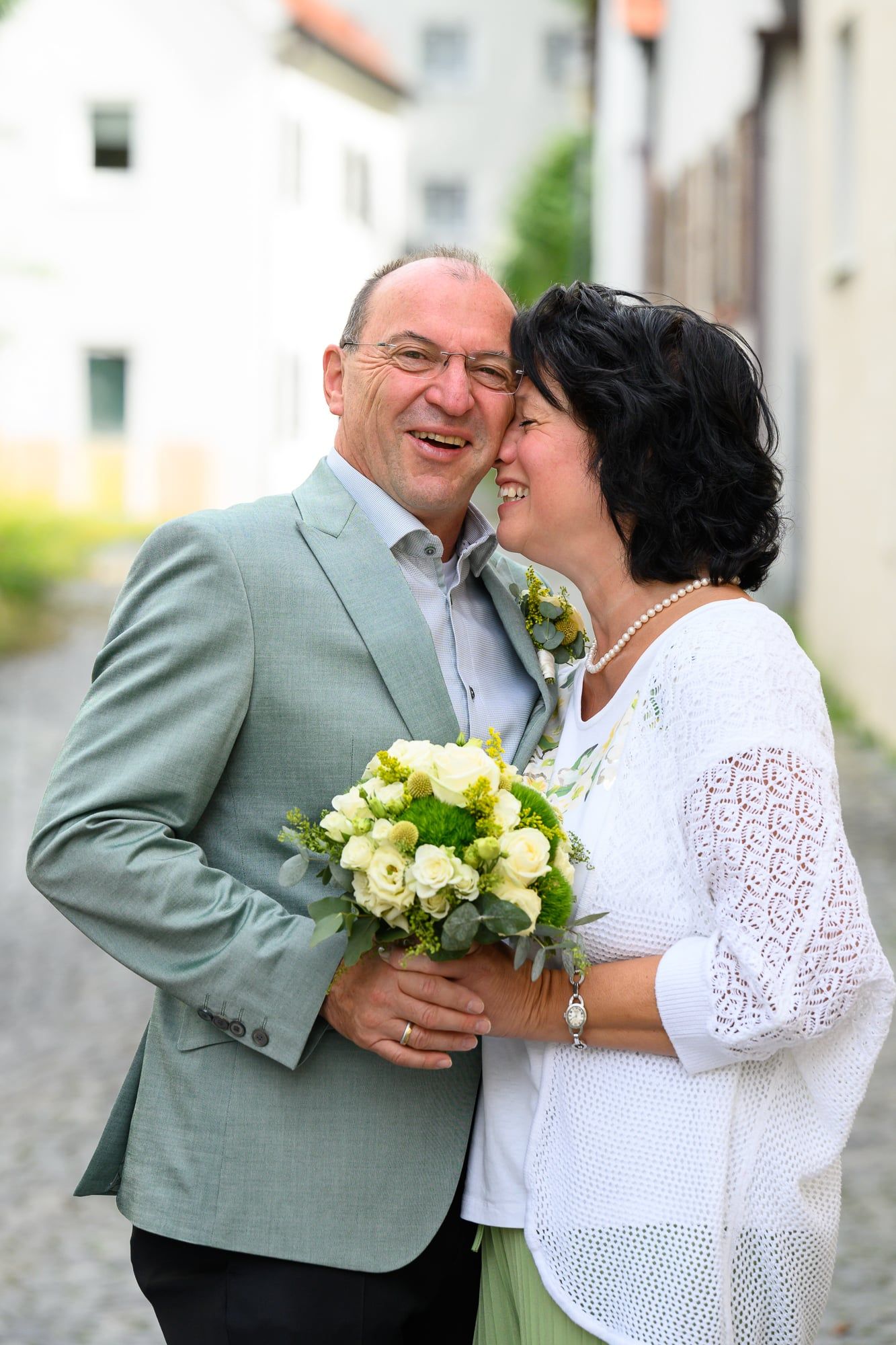 Brautpaar mit Strauß lacht Wange an Wange in einer Altstadtgasse – Hochzeit in Friedberg