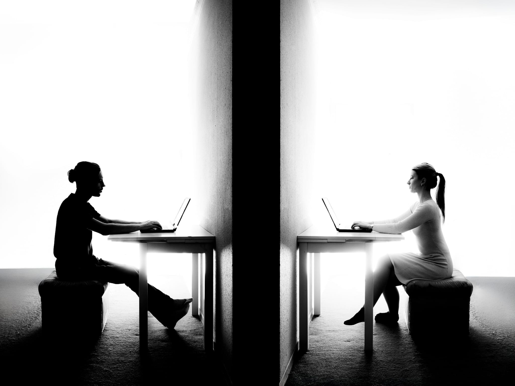 Komposition: Mann und Frau sitzen auf beiden Seiten der Wand jeweils am Laptop