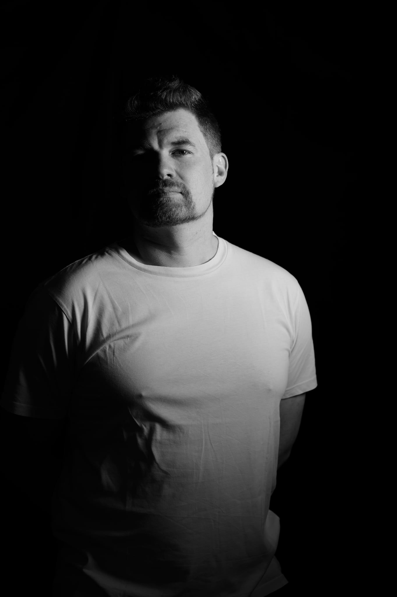 Low-Key-Portrait von Daniel im weißen T-Shirt mit einer Lichtquelle, eine Gesichtshälfte im Schatten