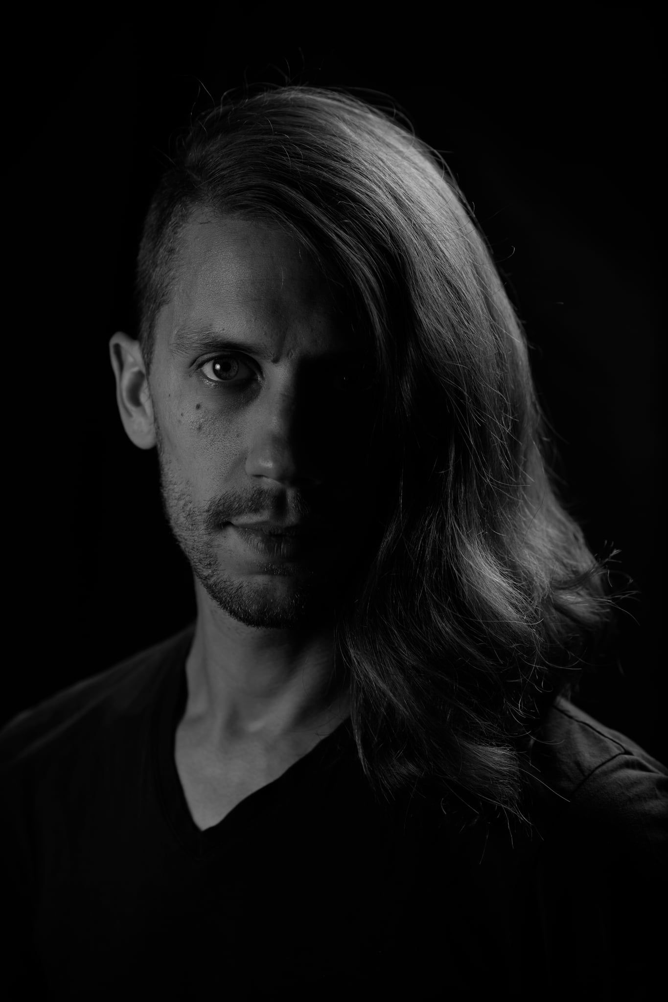 Low-Key-Portrait von Lukas mit langen Haaren, Licht von einer Seite
