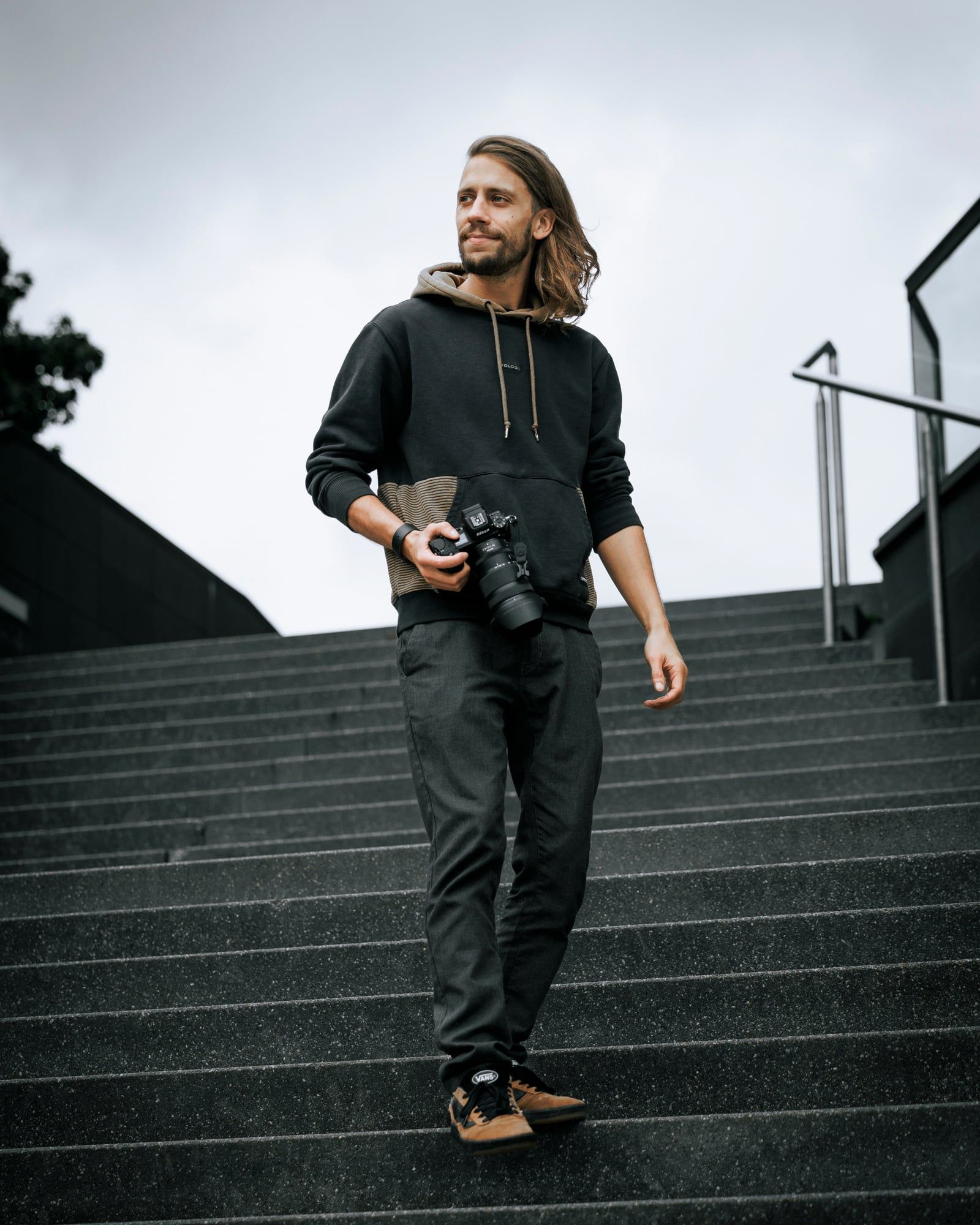 Lukas Frank mit Kamera in der Hand auf einer breiten Steintreppe