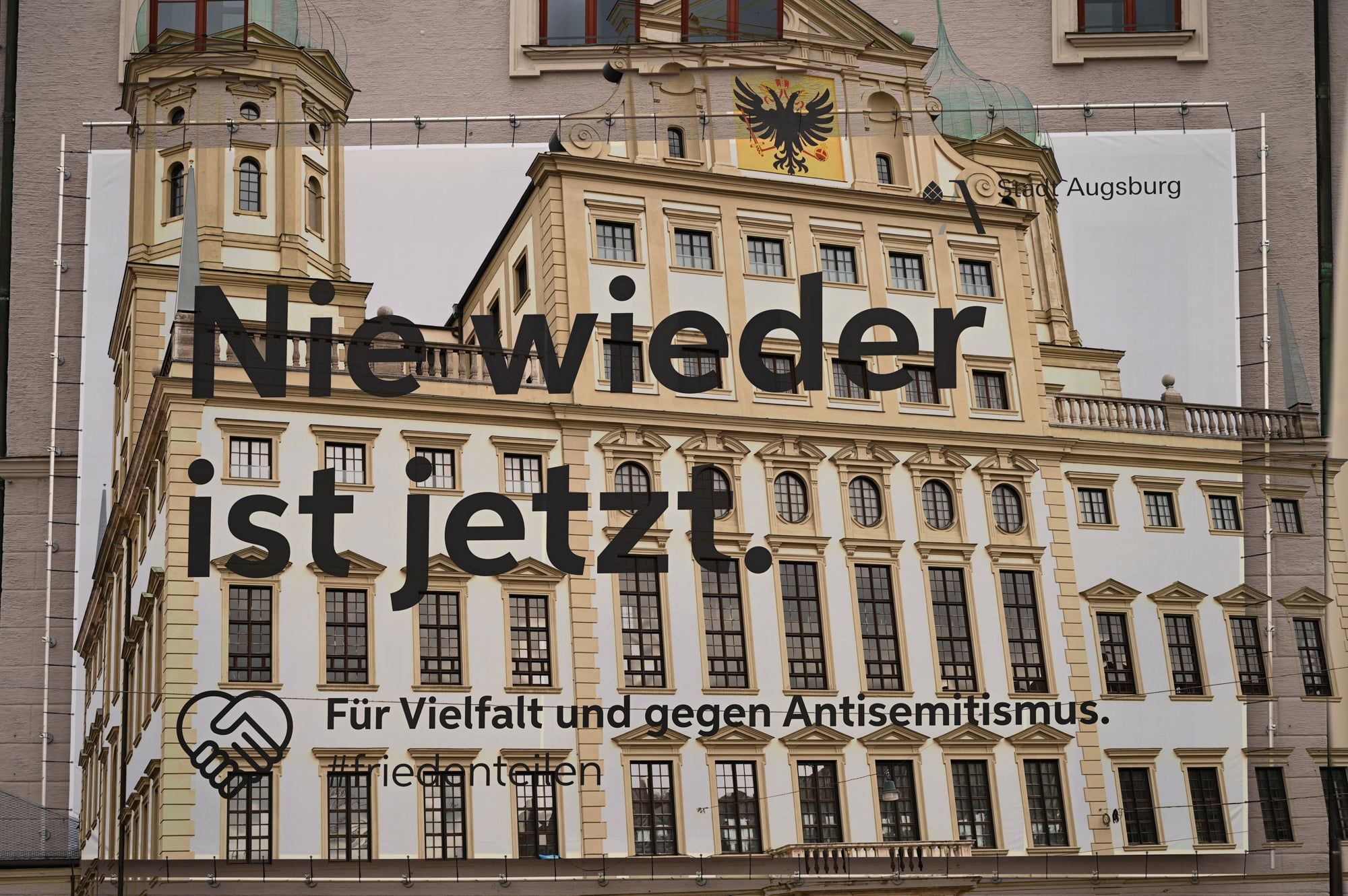 Mehrfachbelichtung: Banner „Nie wieder ist jetzt – für Vielfalt und gegen Antisemitismus“ vor dem Augsburger Rathaus