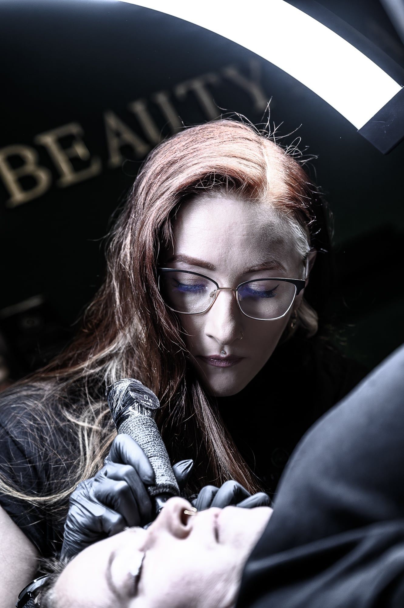 Tätowiererin mit Brille arbeitet konzentriert im Studio Fräuleins Beauty Place in Gersthofen